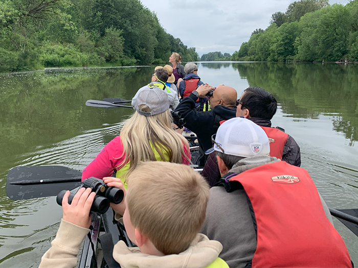 a group of paddlers look upward through binoculars