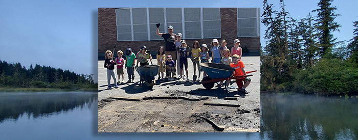 Kids pose next to an area where asphalt has been removed